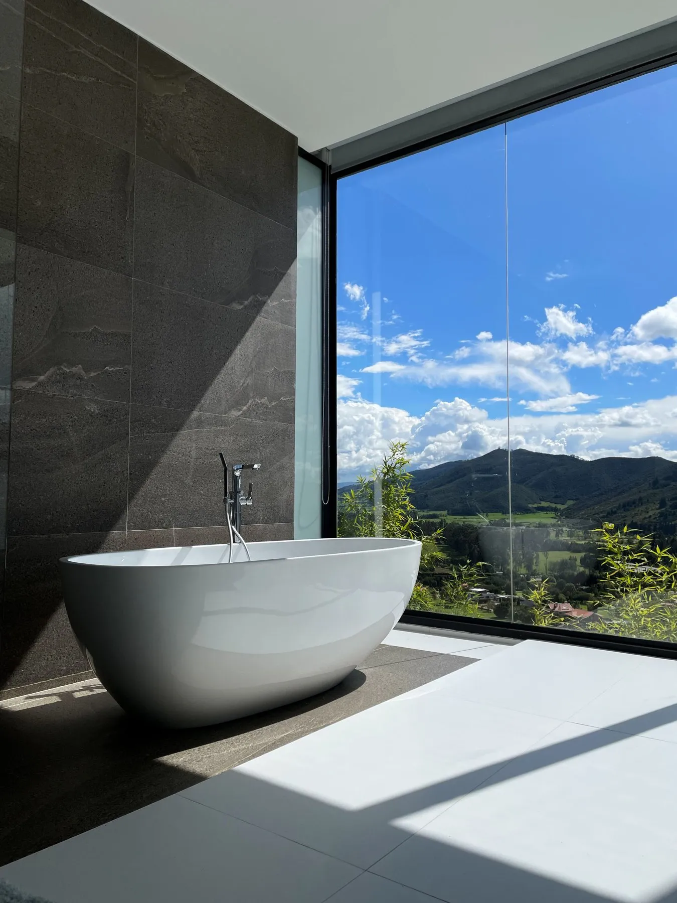 Freestanding bath beside a floor-to-ceiling window